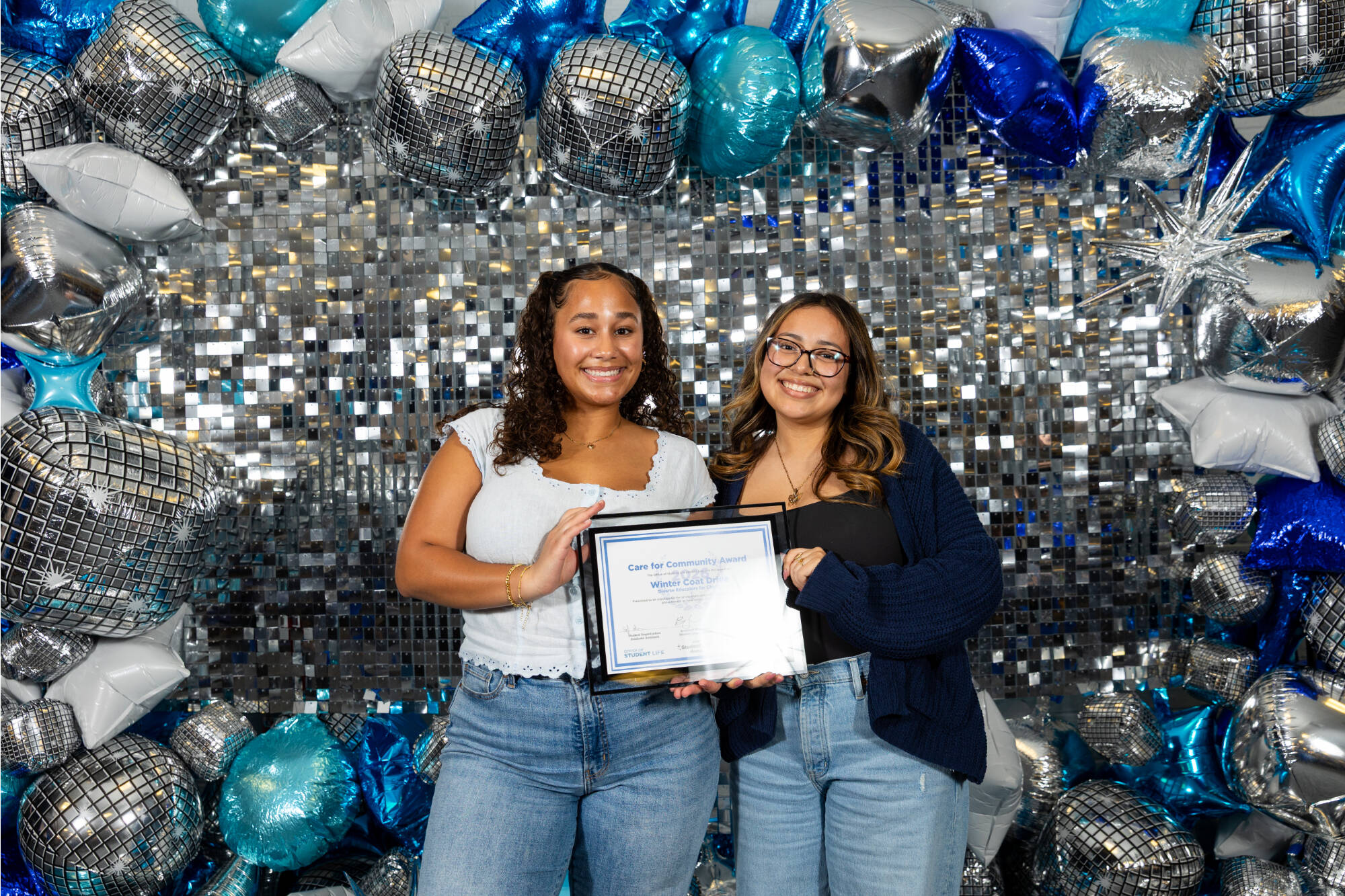 Two individuals holding an award certificate
